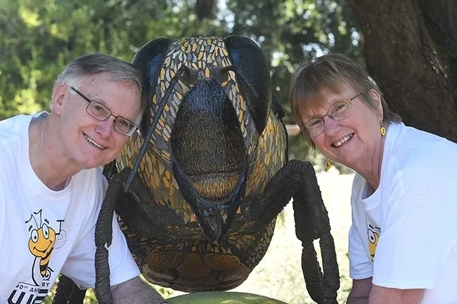 In this 2017 image, Eric Mussen, co-founder and a six-term president of the Western Apicultural Society poses with his wife, Helen, by the ceramic-mosaic sculpture, "Miss Bee Haven," that anchors the UC Davis Bee Haven on Bee Biology Road. The 2017 WAS convention took place at its birthplace, UC Davis. (Photo by Kathy Keatley Garvey)