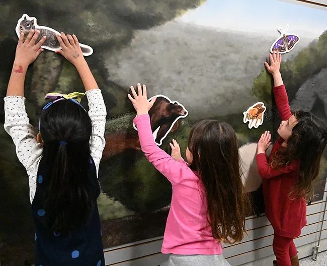 Three youngsters delight in moving wildlife around--a squirrel, a bear, a carpenter bee and a butterfly--at the Bohart Museum of Entomology during the 12th annual UC Davis Biodiversity Museum Day. (Photo by Kathy Keatley Garvey)