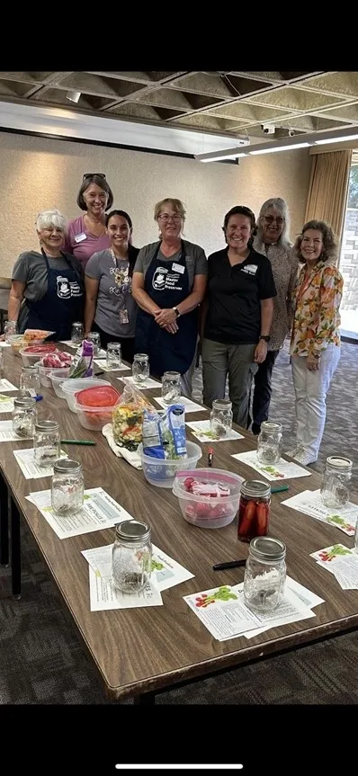 Staff from UCCE standing behind a table that is set-up to teach about preserving and eating healthy.