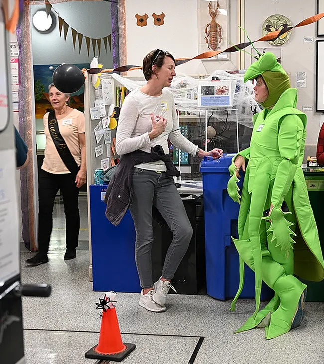A praying mantis pays "no predatory attention" to a queen bee at the Bohart Museum's pre-Halloween party. From left are Lynn Kimsey, director of the Bohart Museum as a queen bee; Kristen Bond, Bohart associate; and Tabatha Yang, Bohart education and outreach coordinator dressed as a mantis. (Photo by Kathy Keatley Garvey)