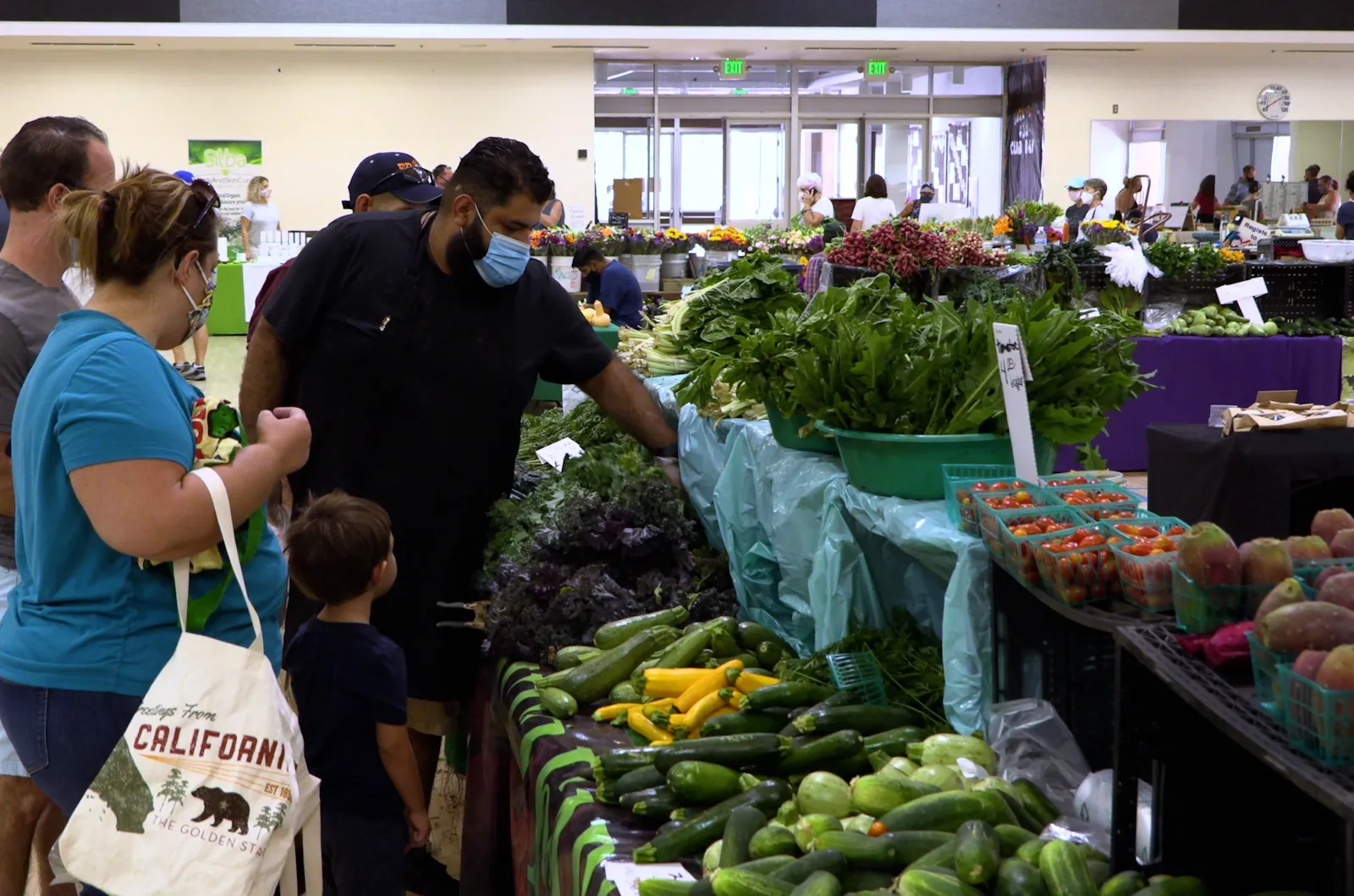 Familias comprando productos frescos en un mercado de granjeros