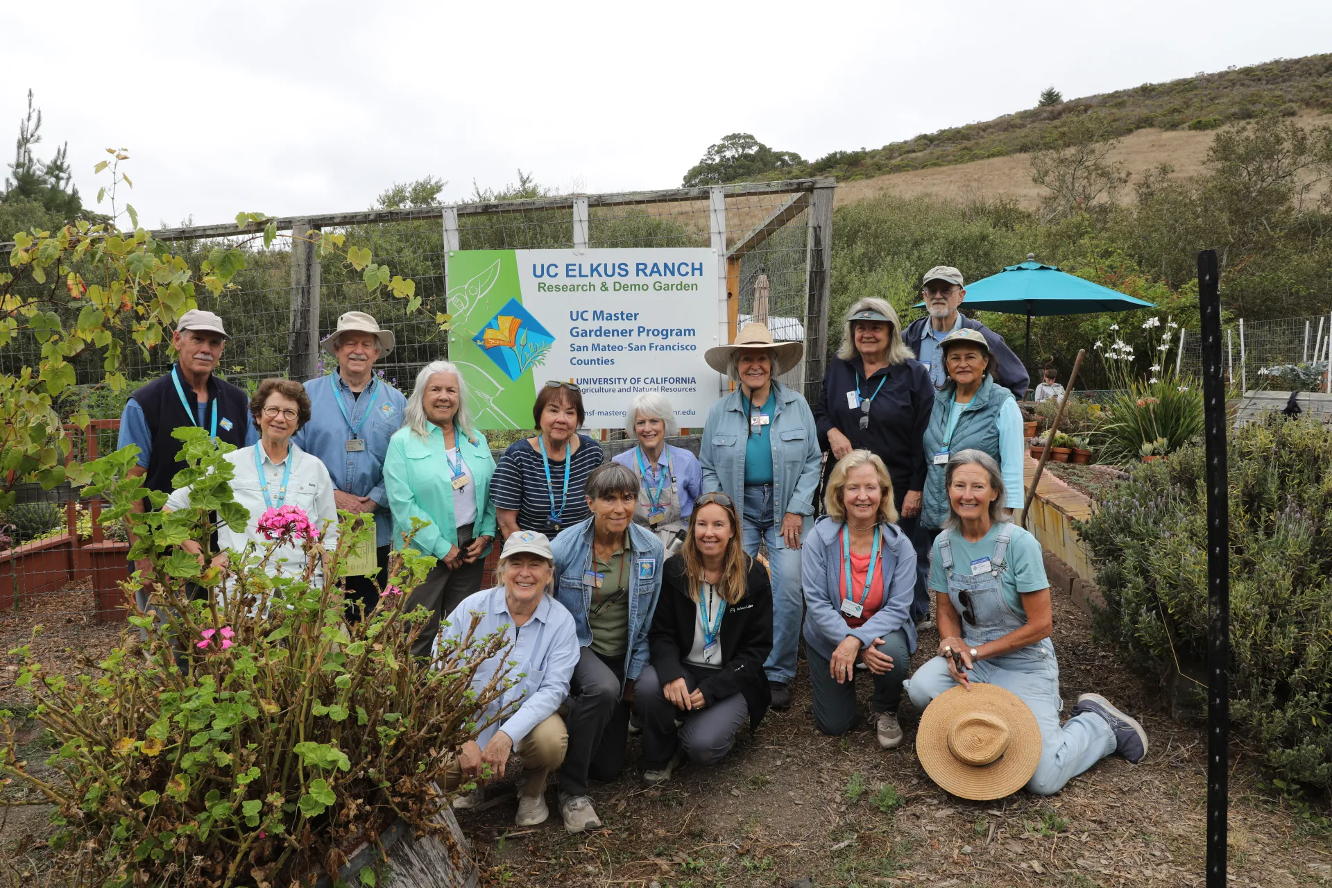 Fifteen people pose in a garden around a sign that reads, "UC Elkus Ranch research & demo garden. UC Master Gardener Program San Mateo-San Francisco counties