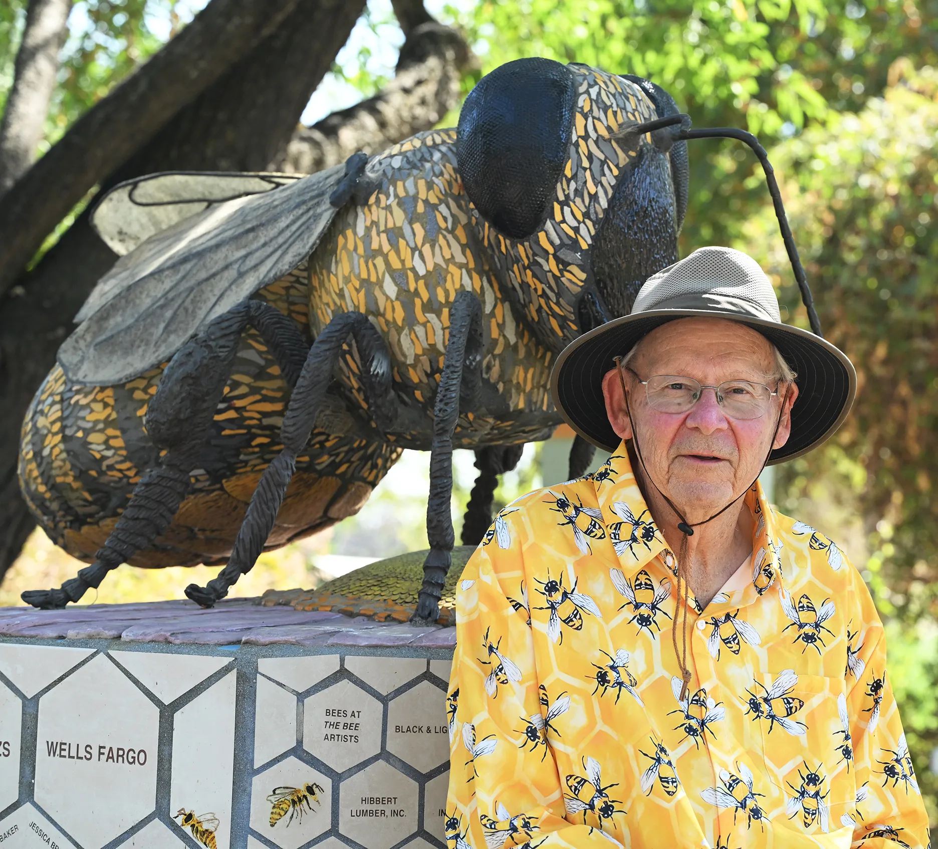 Retired chemist Alan Brattesani, wearing a bee shirt, sits by the worker bee sculpture, the work of Donna Billick. (Photo by Kathy Keatley Garvey)