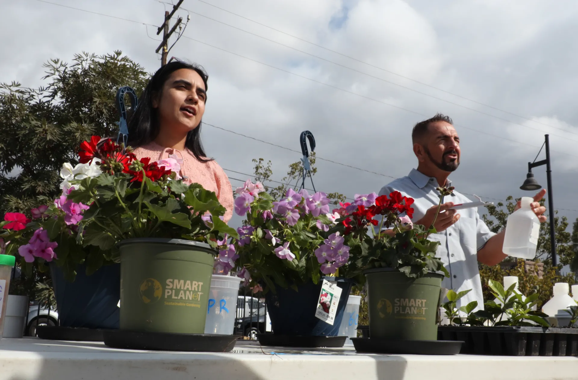 Two people stand over a table with plants on it