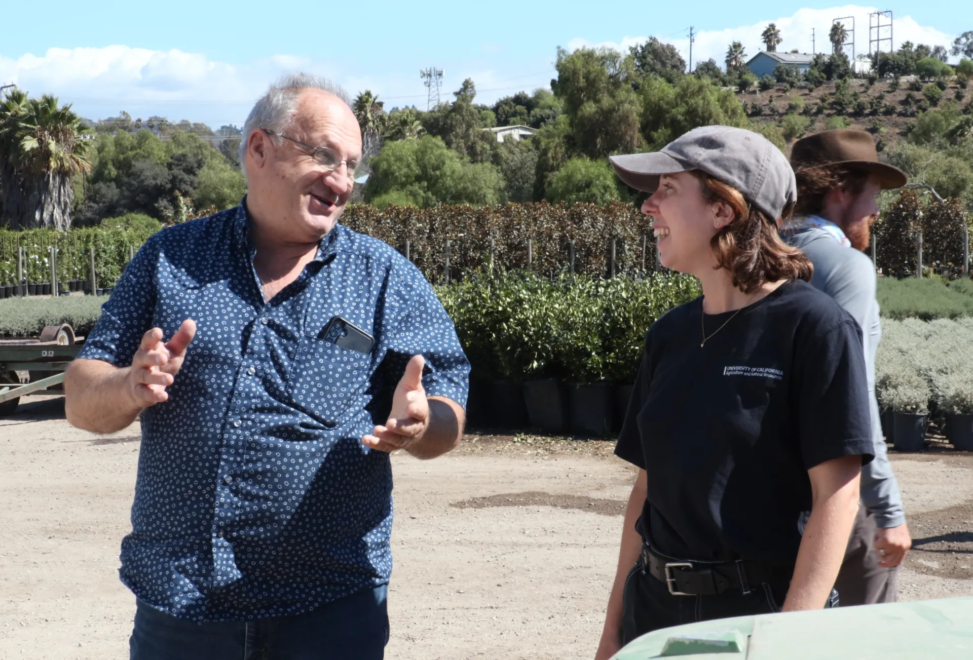 Two people talk outside at a plant nursery