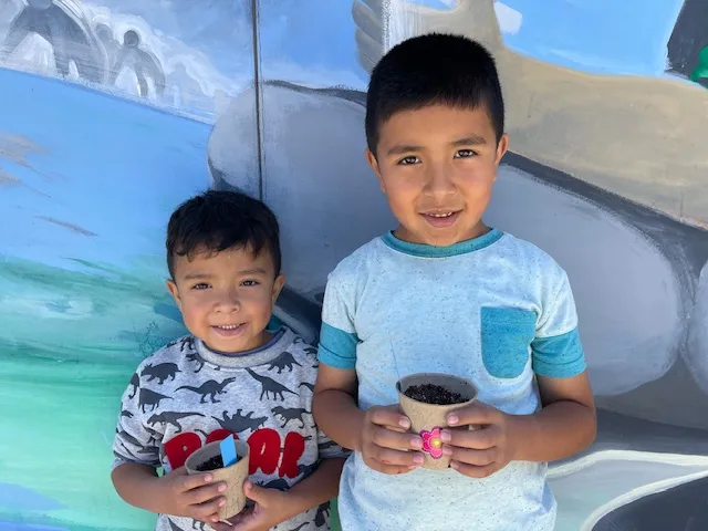 two young boys holding recently planted seeds