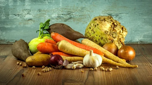 a variety of root vegetables piled on a wooden table