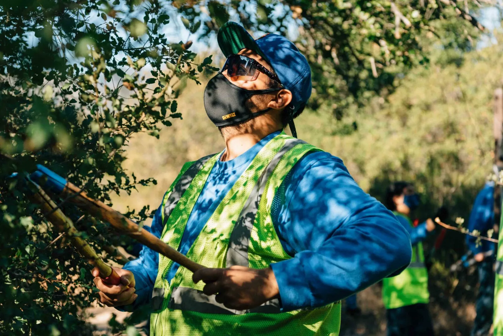 A young Corps Member using lopers to trim a tree