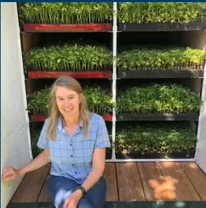 Woman sitting in front of racks of vegetable transplants
