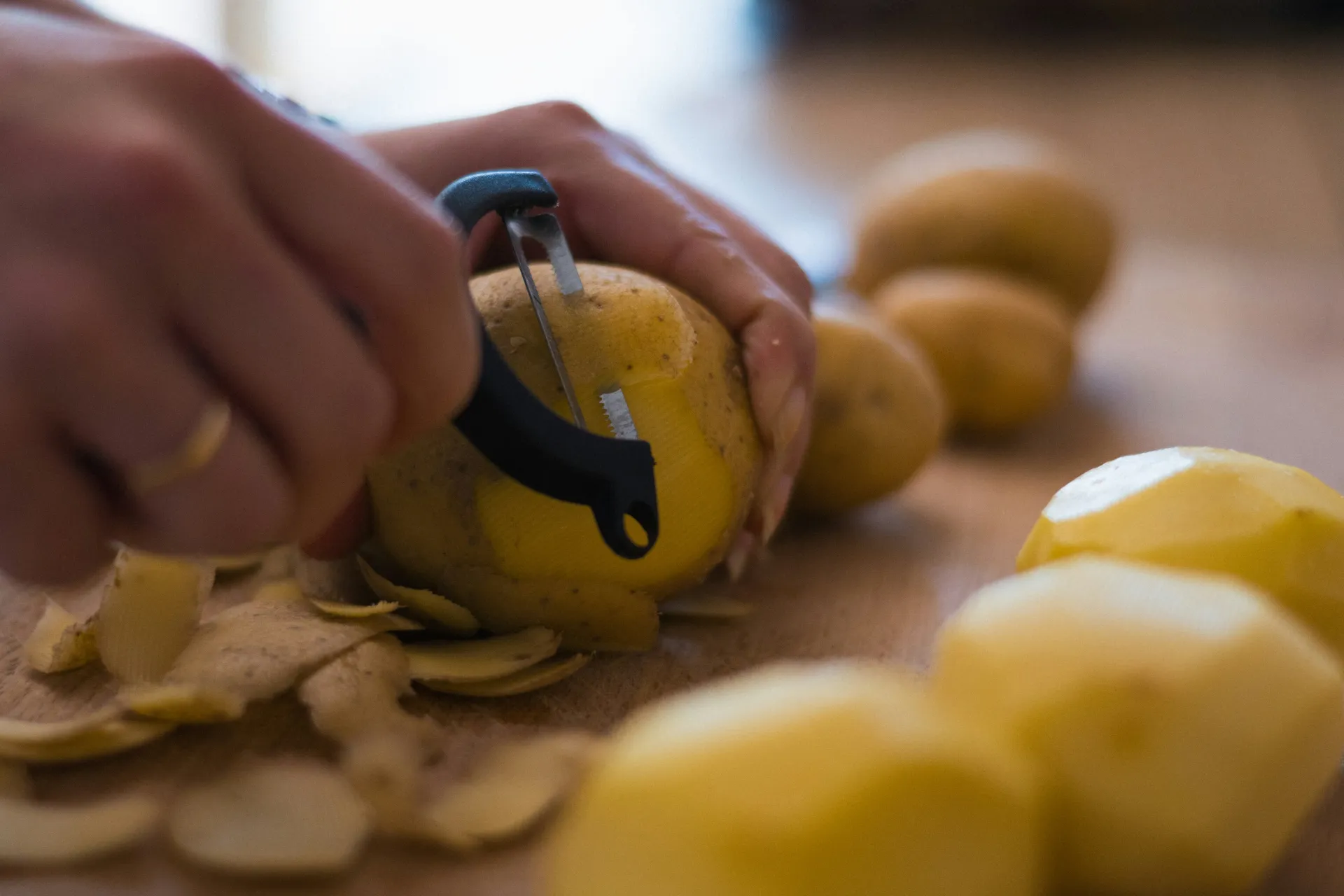 hands peeling potatoes on a countertop