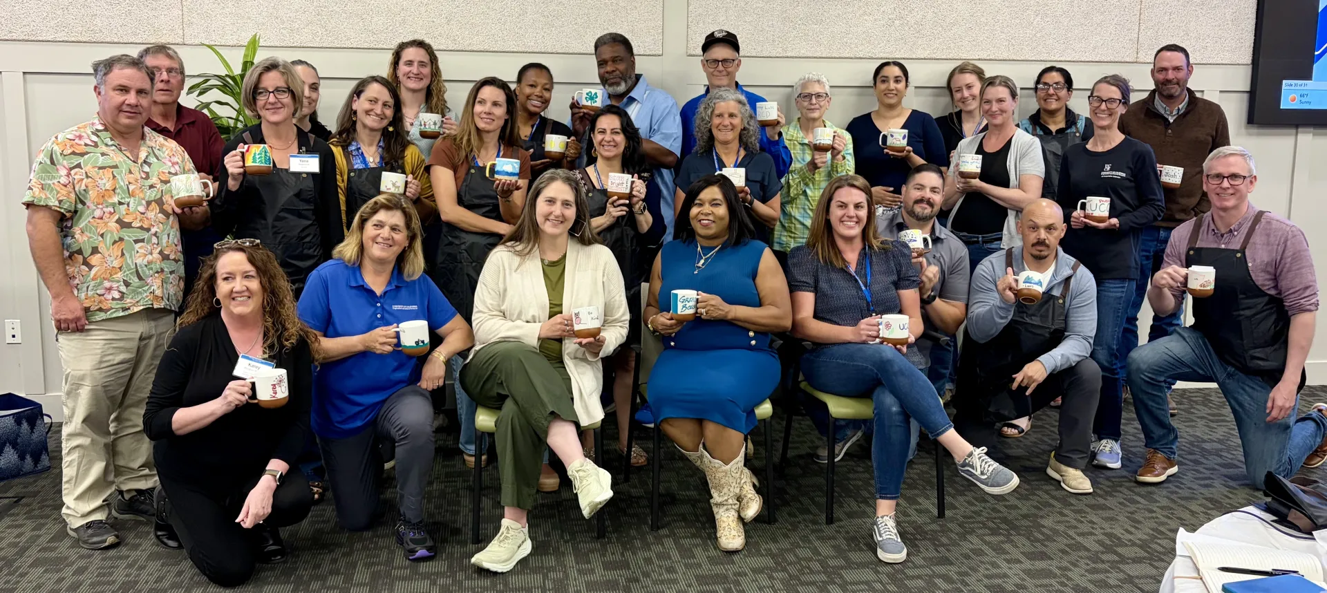 Group shot of 27 people holding up decorated mugs