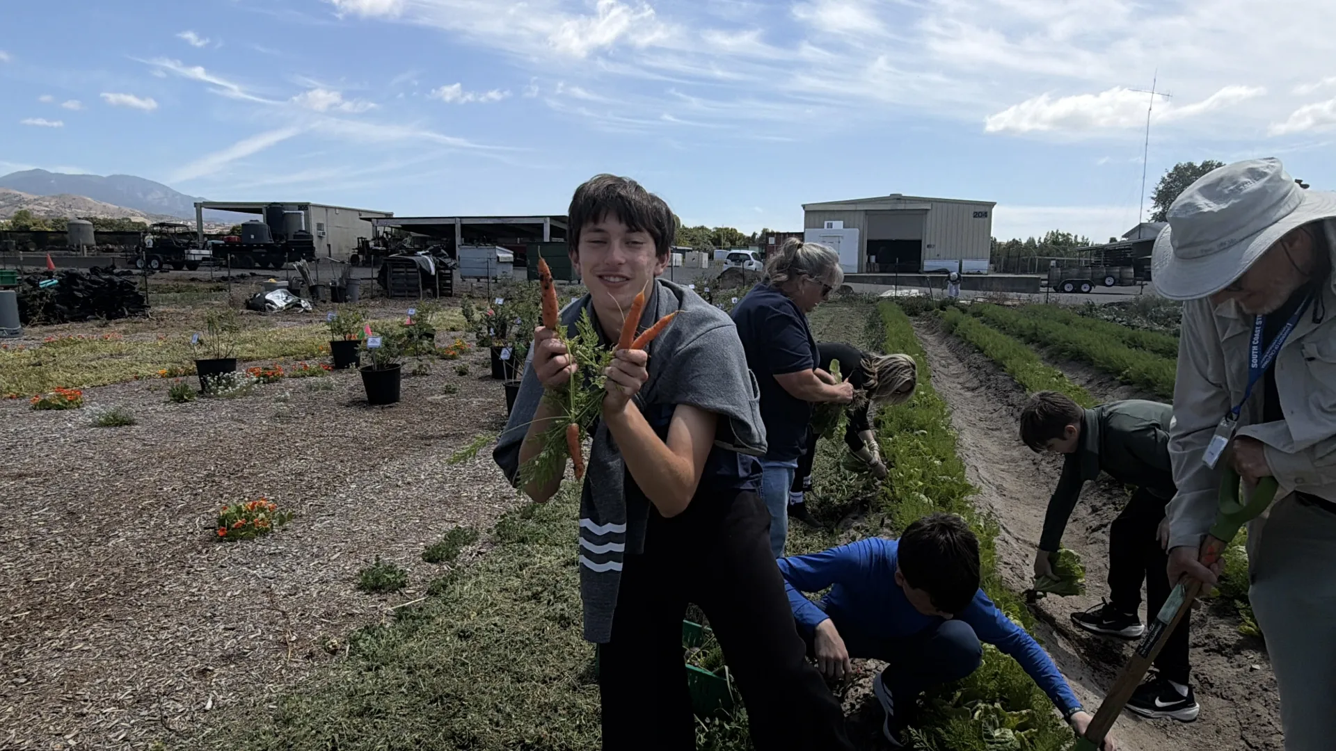 Un niño muestra un racimo de zanahorias a la cámara.
