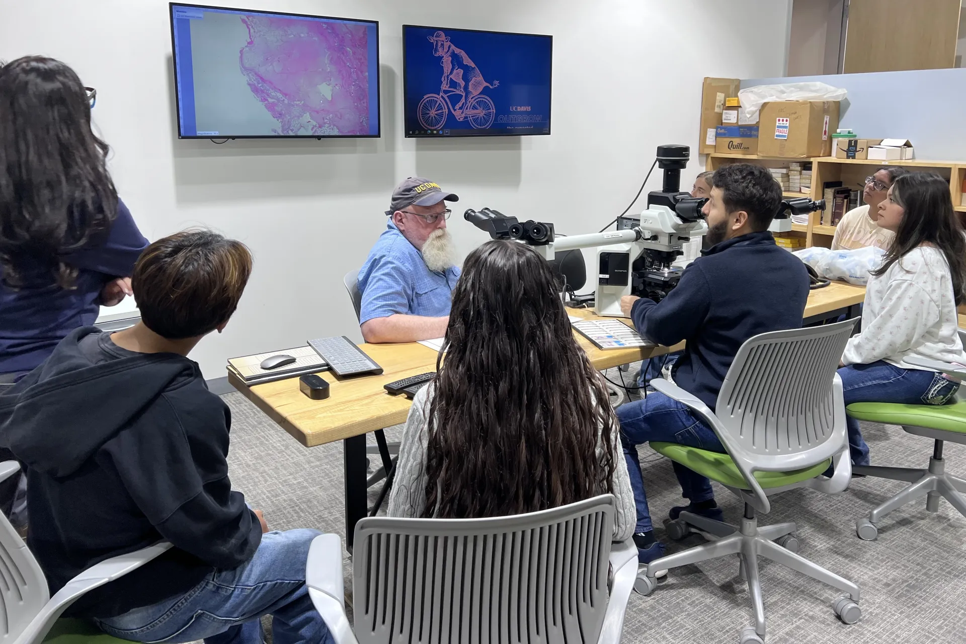 Man leads interns in a discussion on histopathology as they all sit around a table