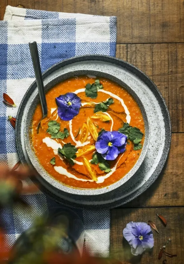 Soup garnished with pansies and cilantro. 
