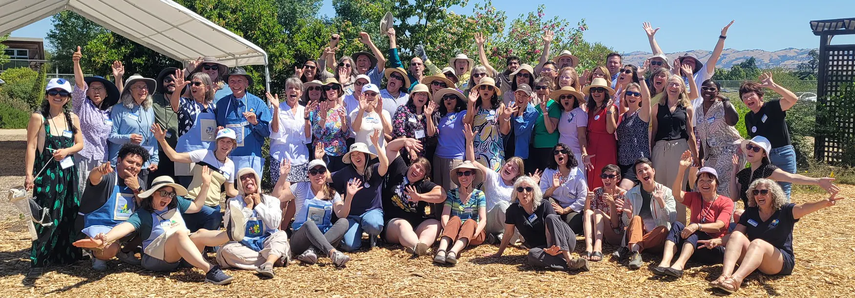 A large group of people joyfully waving their hands and hats