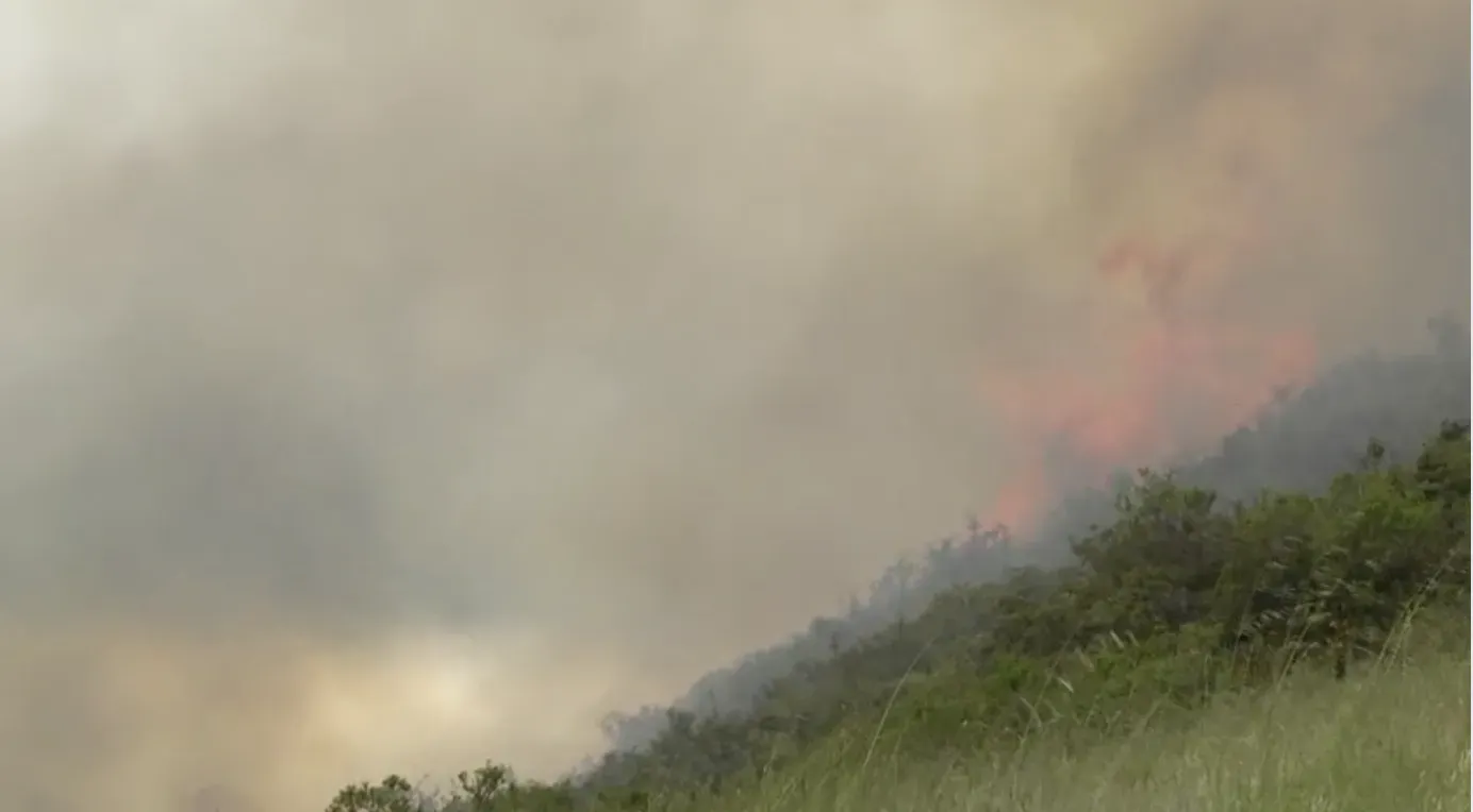 Grass fire flames and smoke traveling uphill