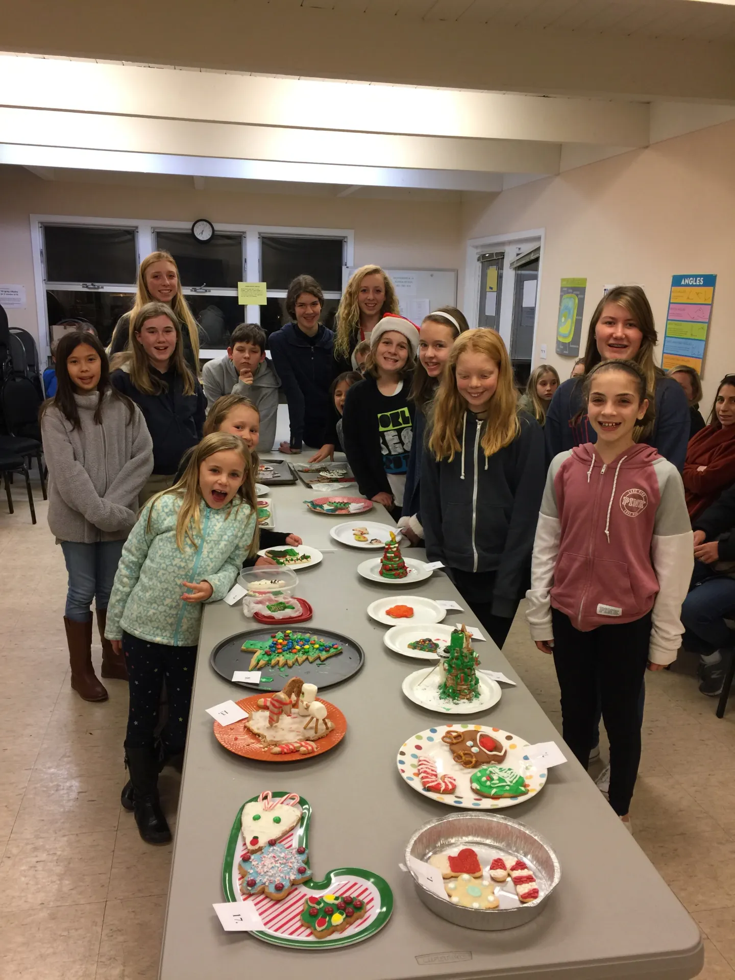 a group of kids with a table full of Christmas cookies