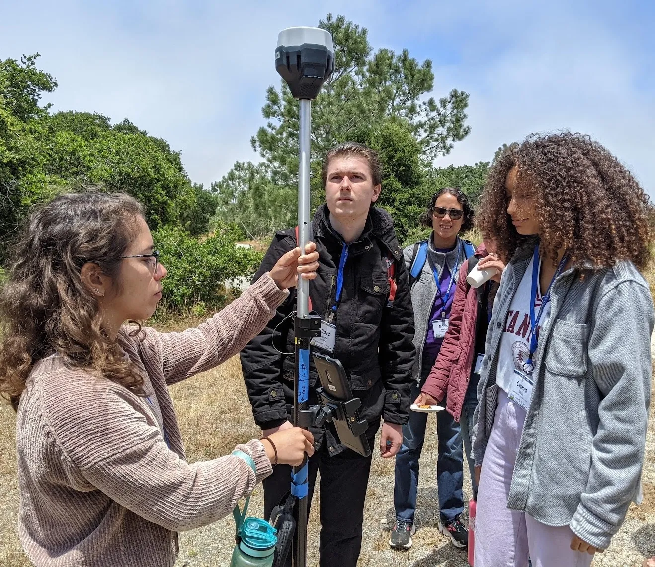 Three people stand around a handheld remote sensing tool