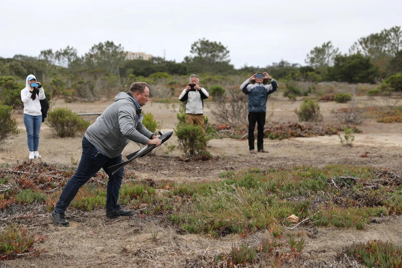 A person launches a drone while people take photos