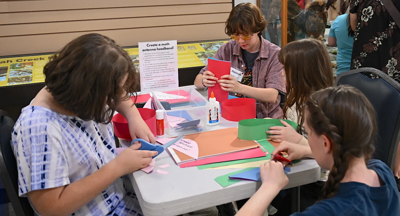 Bohart Museum intern Hannah Petok (back) shows how to make moth antennae headbands.