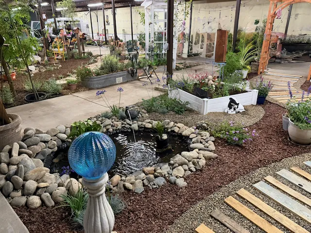 View of right rear and center of garden plot, showing pond with duck fountain, an herb garden, walkway, and arbor.