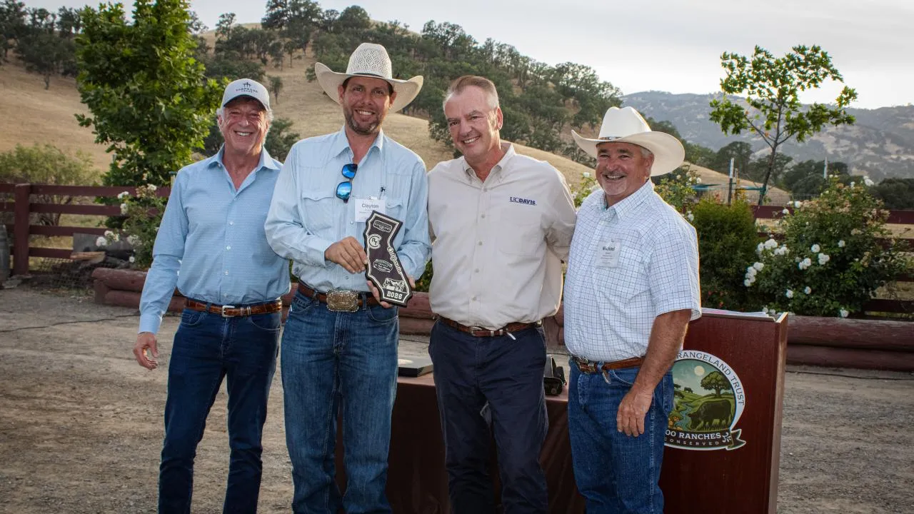 A group of four people stand holding an award