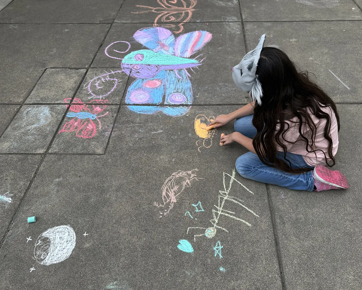 A girl creating chalk art at the 2025 Bohart Museum of Entomology open house.