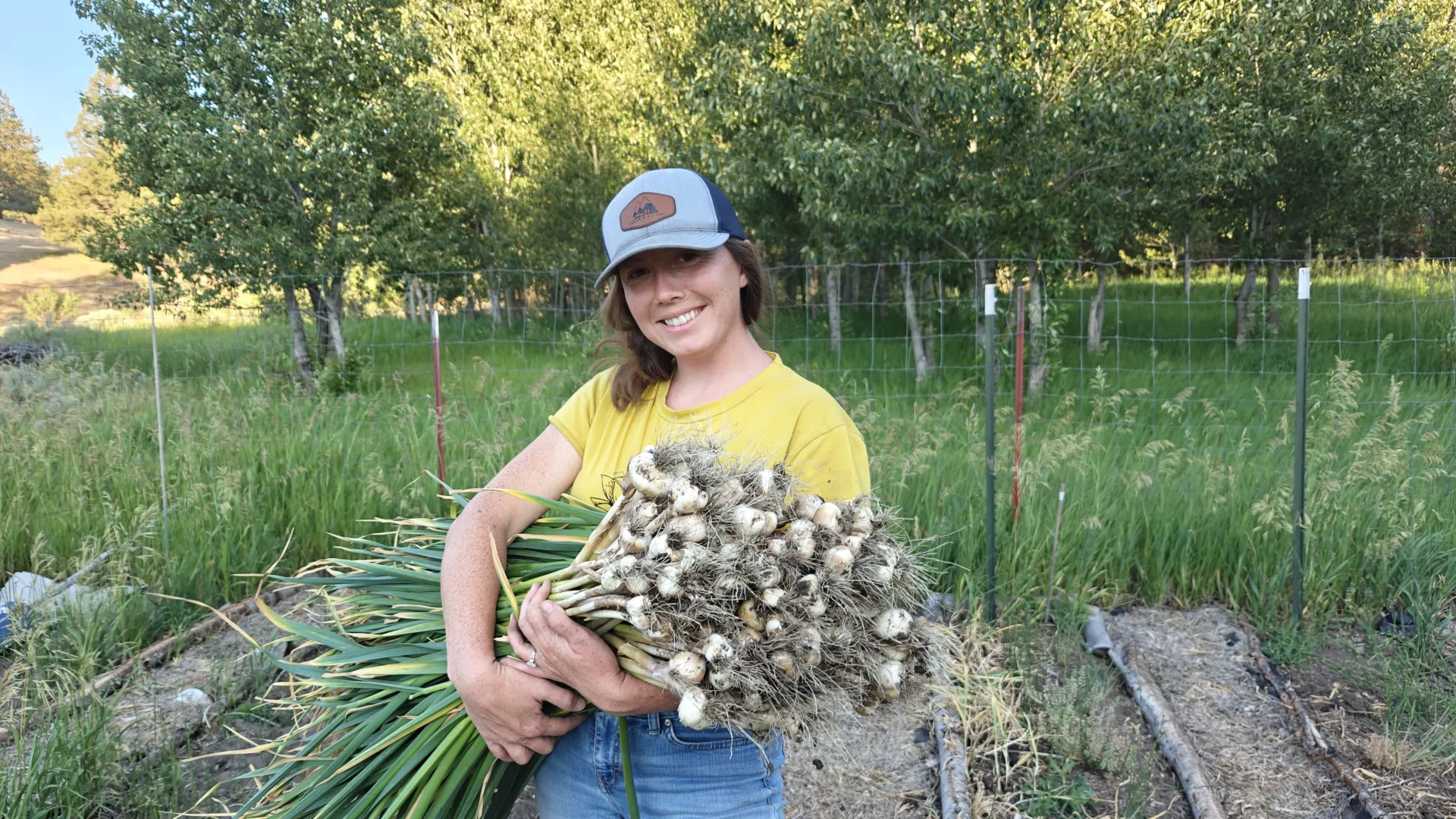 Ary West holds a freshly harvested armful of garlic at Trouble Valley Farm, her diversified farmstead outside Alturas