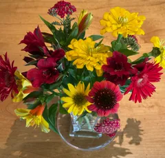 vase of cut flowers including native plant red Achillea millefolium, and yellow and red Alstroemeria, yellow Zinnias, and fuchsia and yellow Cosmos