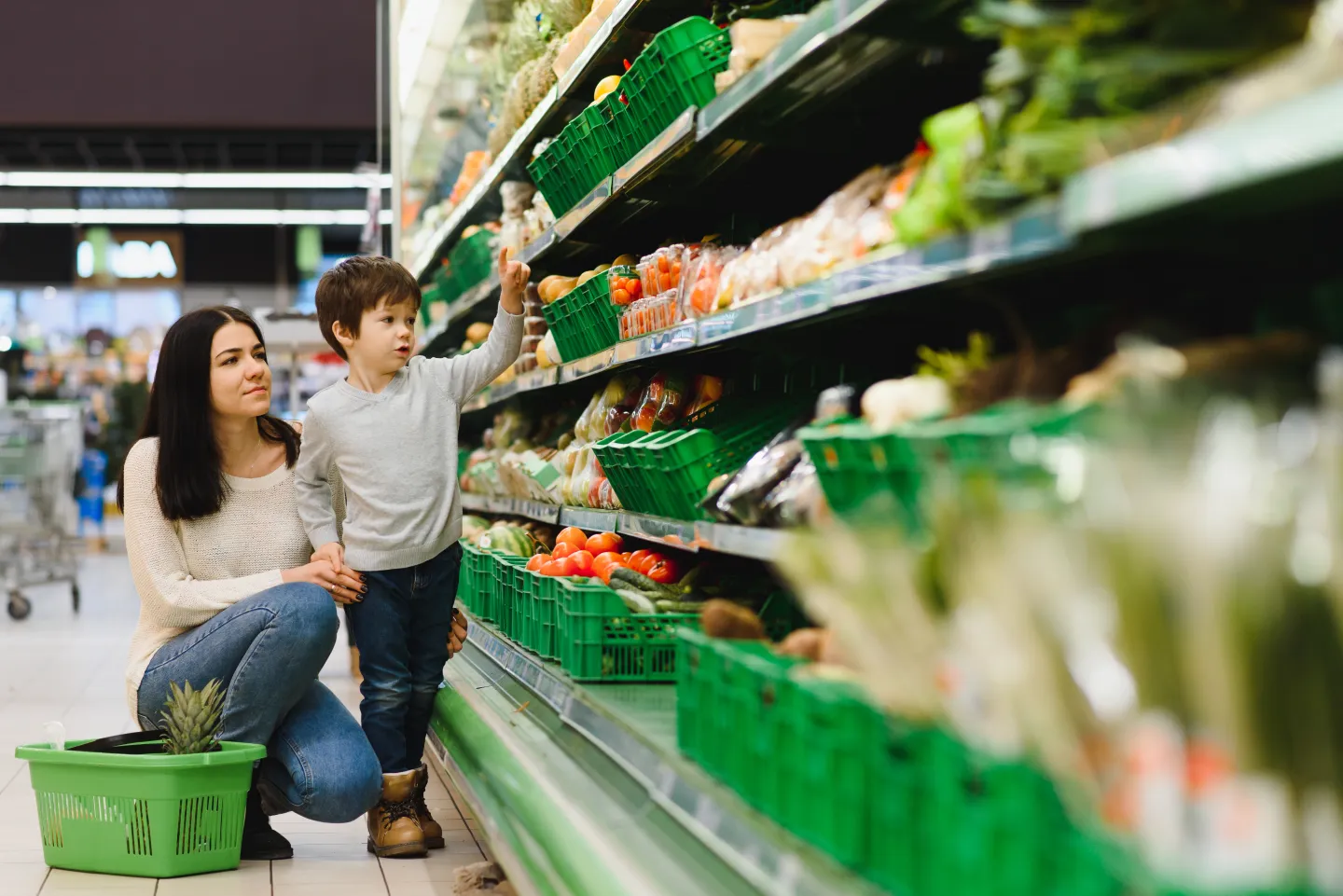 Mother and son shopping in the produce section of a grocery store.