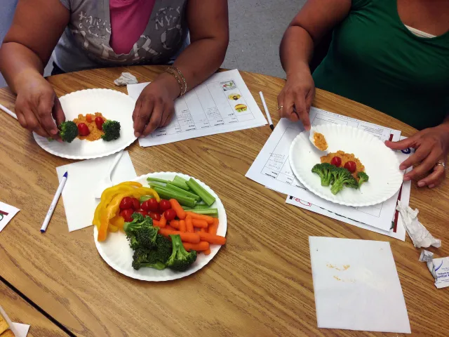 Parents make veggie plates with hummus for their kids.
