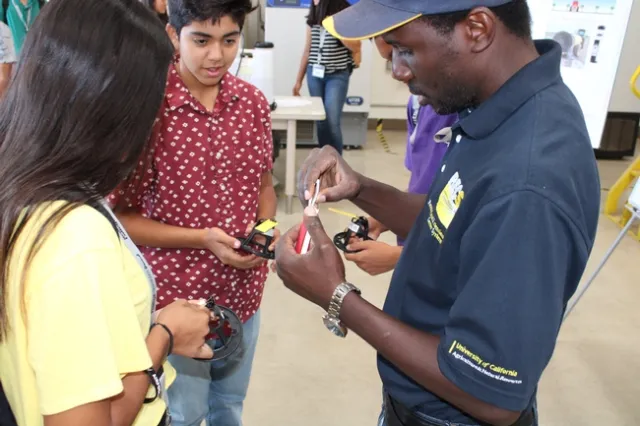 Dr. Peter Larbi interacting with student volunteers to demonstrate spray coverage during workshop.