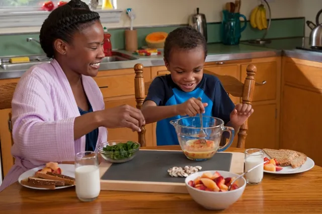 A caregiver and child beating eggs in the kichent - photo SDA's Food and Nutrition Service (FNS), Supplemental Nutrition Assistance Program.