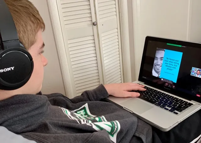 Youth with headphones looking at laptop screen showing a presentation