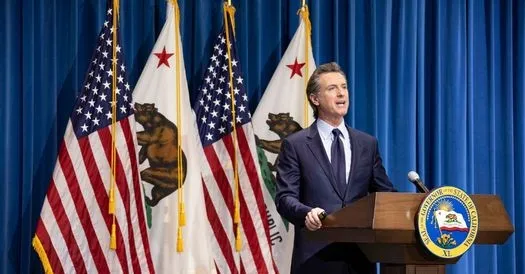 The governor stands at a lectern in front of four flags -- 2 US flags and 2 California flags alternating.
