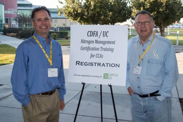 Two men stand by sign that reads: CDFA/UC Nitrogen Management Certification Training for CCAs. Registration