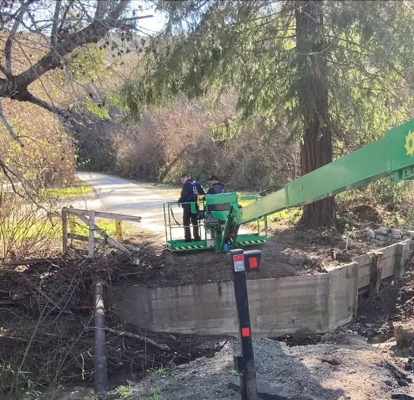Two men stand on a green platform as the machine lowers them to the ground.