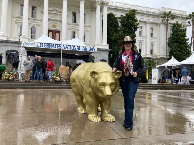 Julia poses beside a gold statue of a bear.