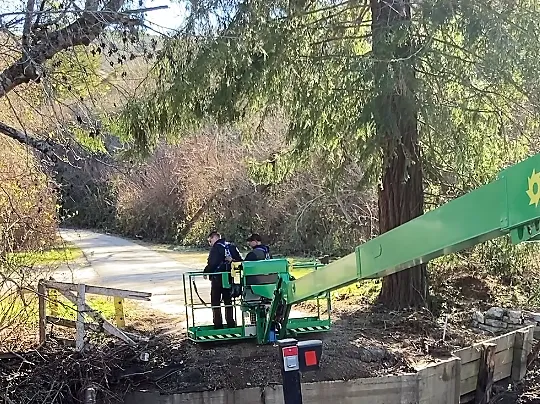 The manlift bucket ferries staff across the creek.