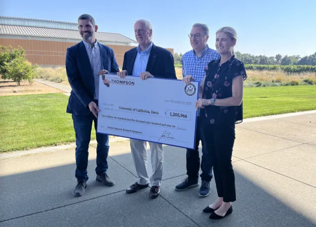 Four people hold a large ceremonial check for $1,205,966.