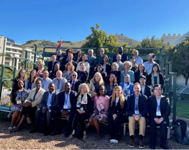 About 40 people sit in bleachers outdoors for a group photo.