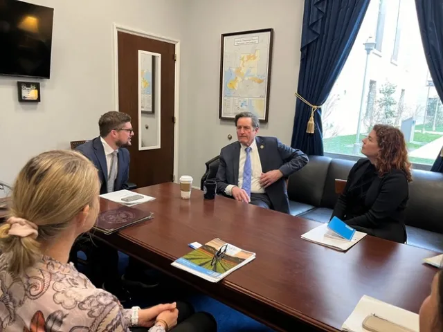 Four people sit around a conference table.