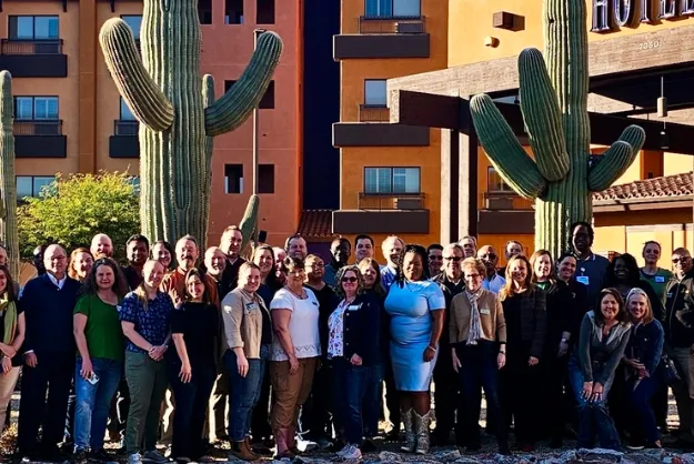 Group of people flanked by two large saguaro cacti.