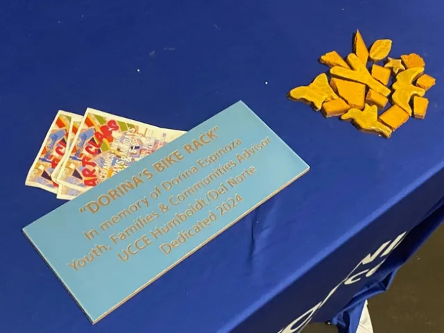 A light blue tile engraved with gold letters reads: