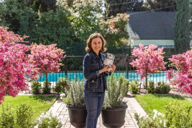 Barbara Vartan holds a photo of herself as a toddler enjoying the backyard at what is now the Clark/Kendrick home. (Photo: Sarah del Pozo)