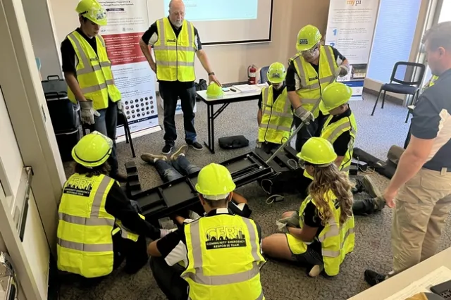 Siempre bajo la mirada vigilante de los capacitadores del programa nacional PyPI, los participantes en el taller, incluyendo a los jóvenes, practican el uso de una palanca para liberar a una persona de un objeto pesado. Fotografía por Ryan Akers.