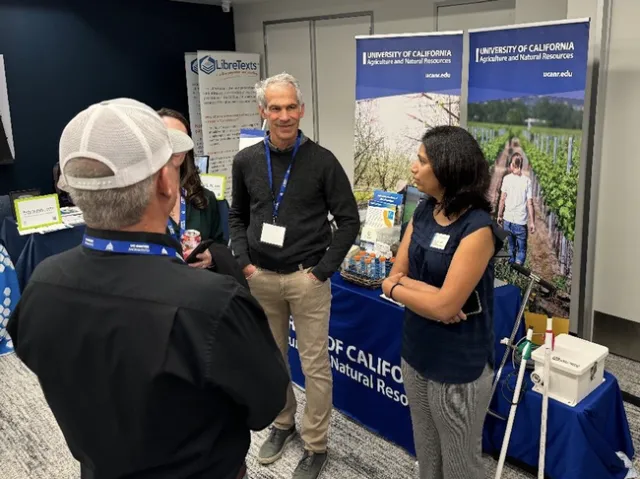 Four people stand and converse at a display booth