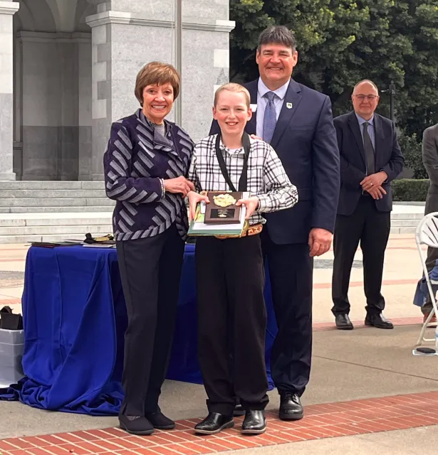 Josiah standing with Karen Ross and Rob Peterson holding his award