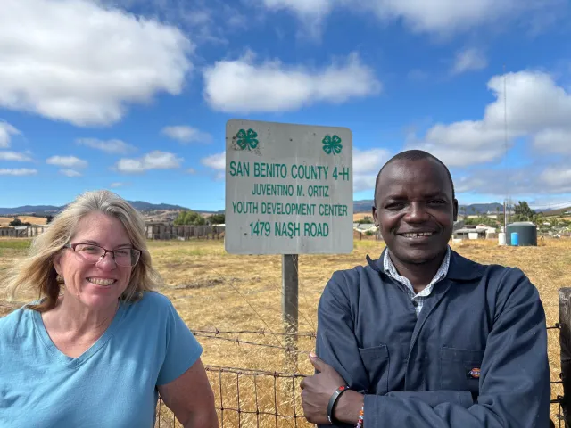 Two people stand next to a field outside a 4-H center