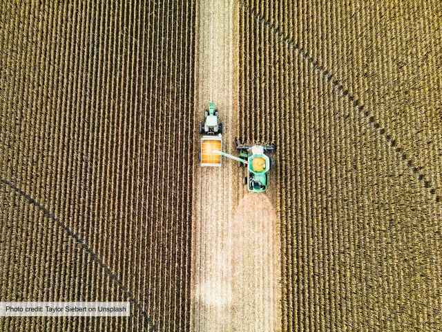 Aerial view of harvester driving through crop field 